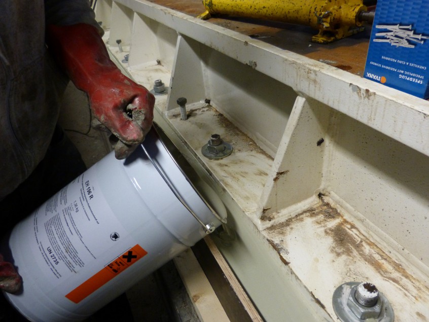 Gieten van gietmortel onder een stalen constructie voor het opvullen en verankeren.